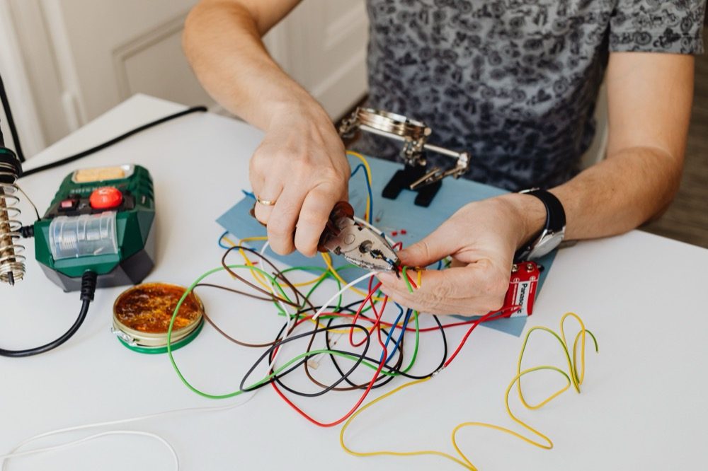 An electrician stripping and organizing wiring with pliers