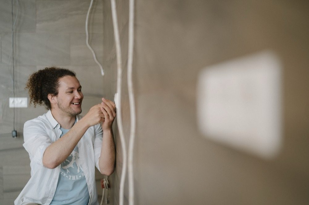 An electrician fitting a wall outlet in a home